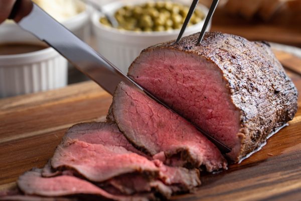 slicing eye of round roasted beef with knife
